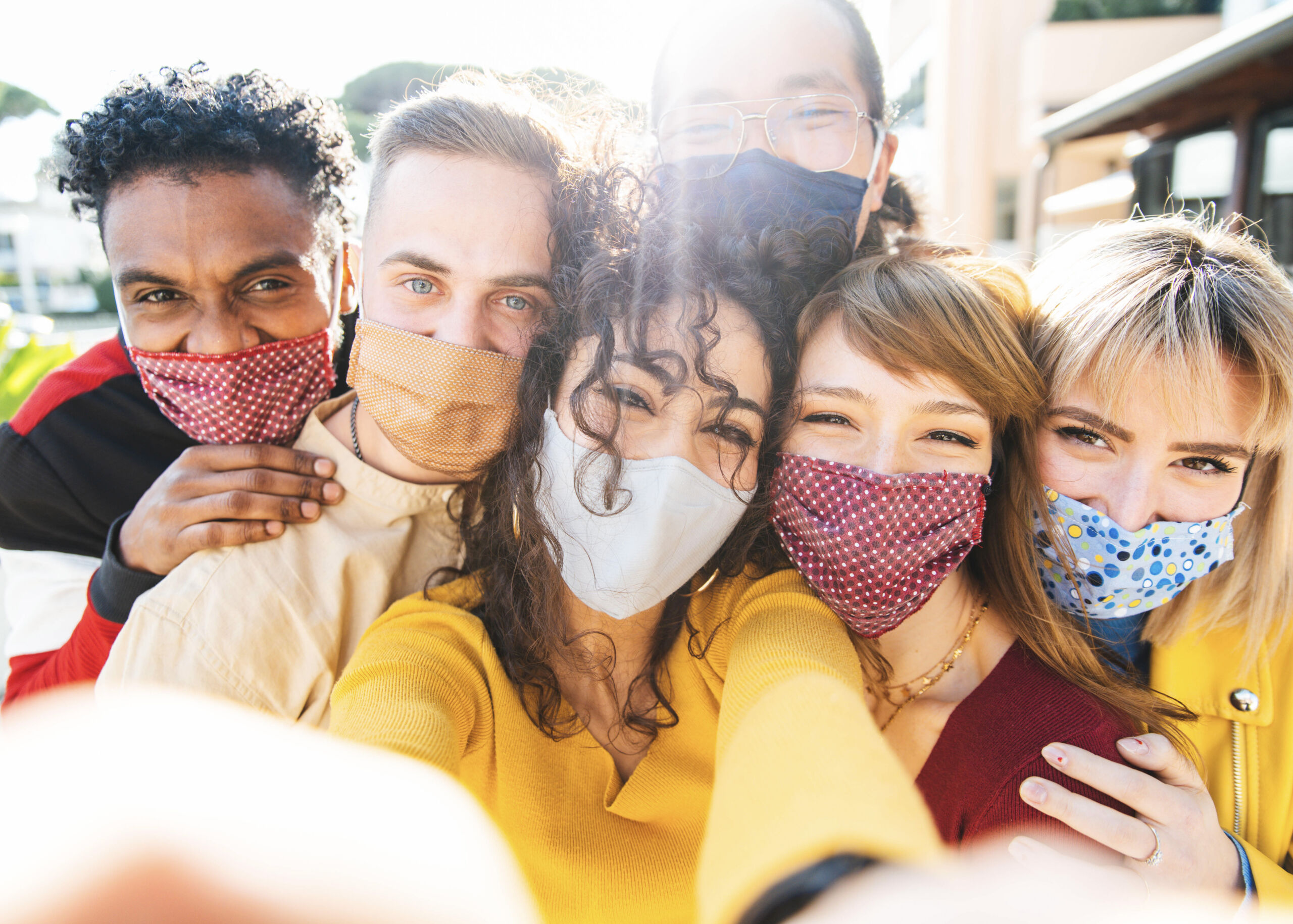 multicultural friends covered by face masks taking a selfie outdoor new normal friendship concept with young people smiling and having fun bright filter