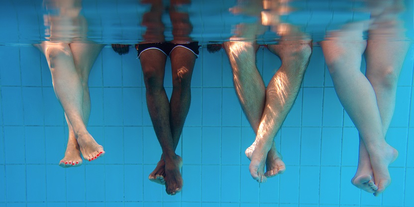 four people legs underwater in the swimming pool. friends. party