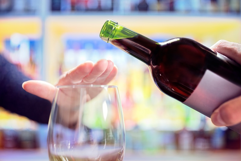 woman hand rejecting more alcohol from wine bottle in bar