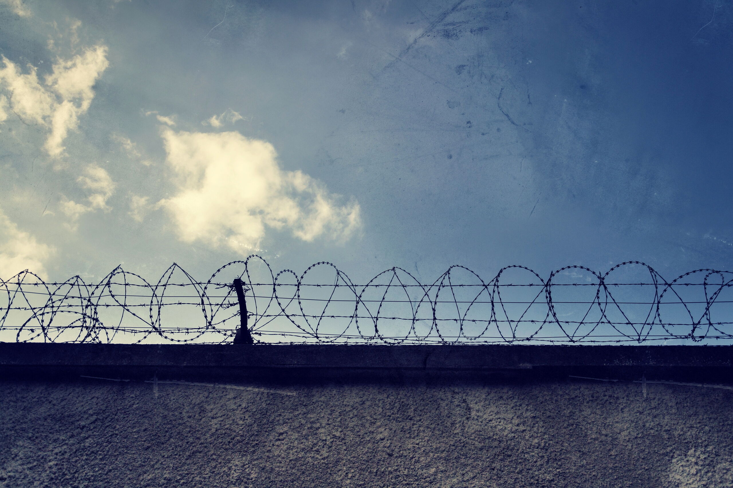 filtered vintage picture of barbed wire prison fence detail