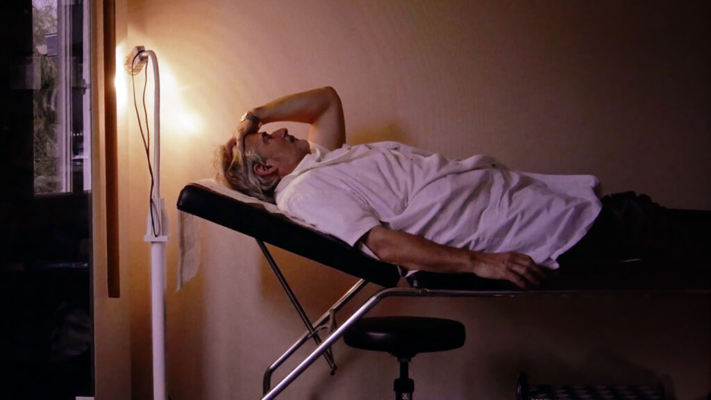 Alain se repose avant de retourner voir ses patients - Photogramme du film "La Tristesse un peu, la passion toujours" ©milleetunefilms