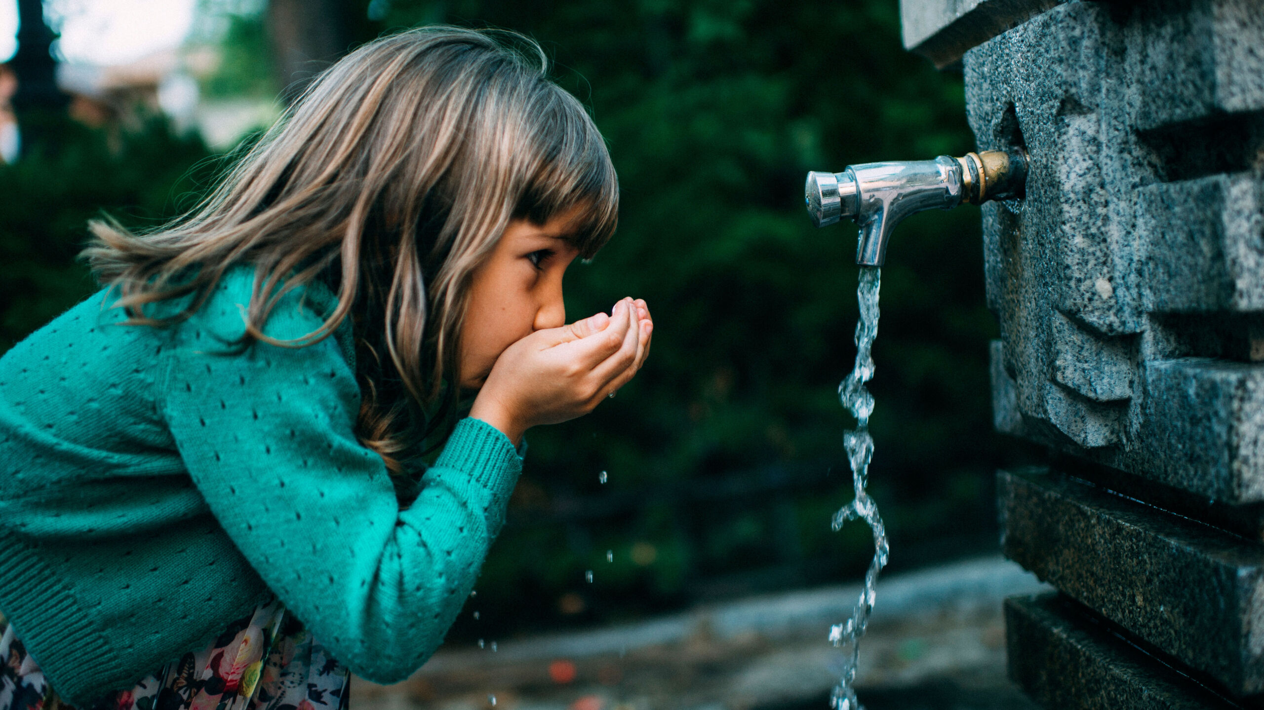 girl drinking water from a fountain