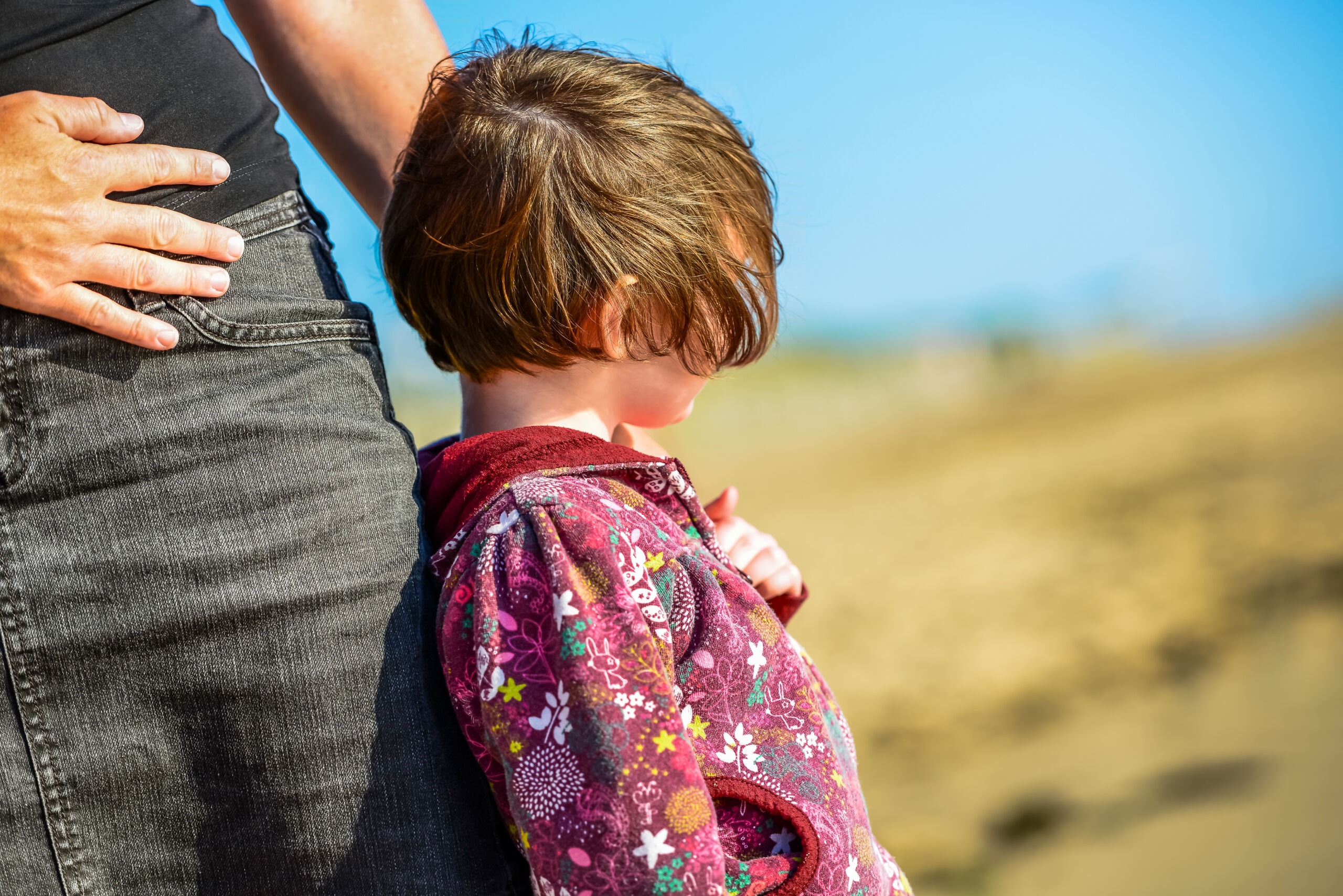 petite fille qui s'appuie sur la jambe de sa maman