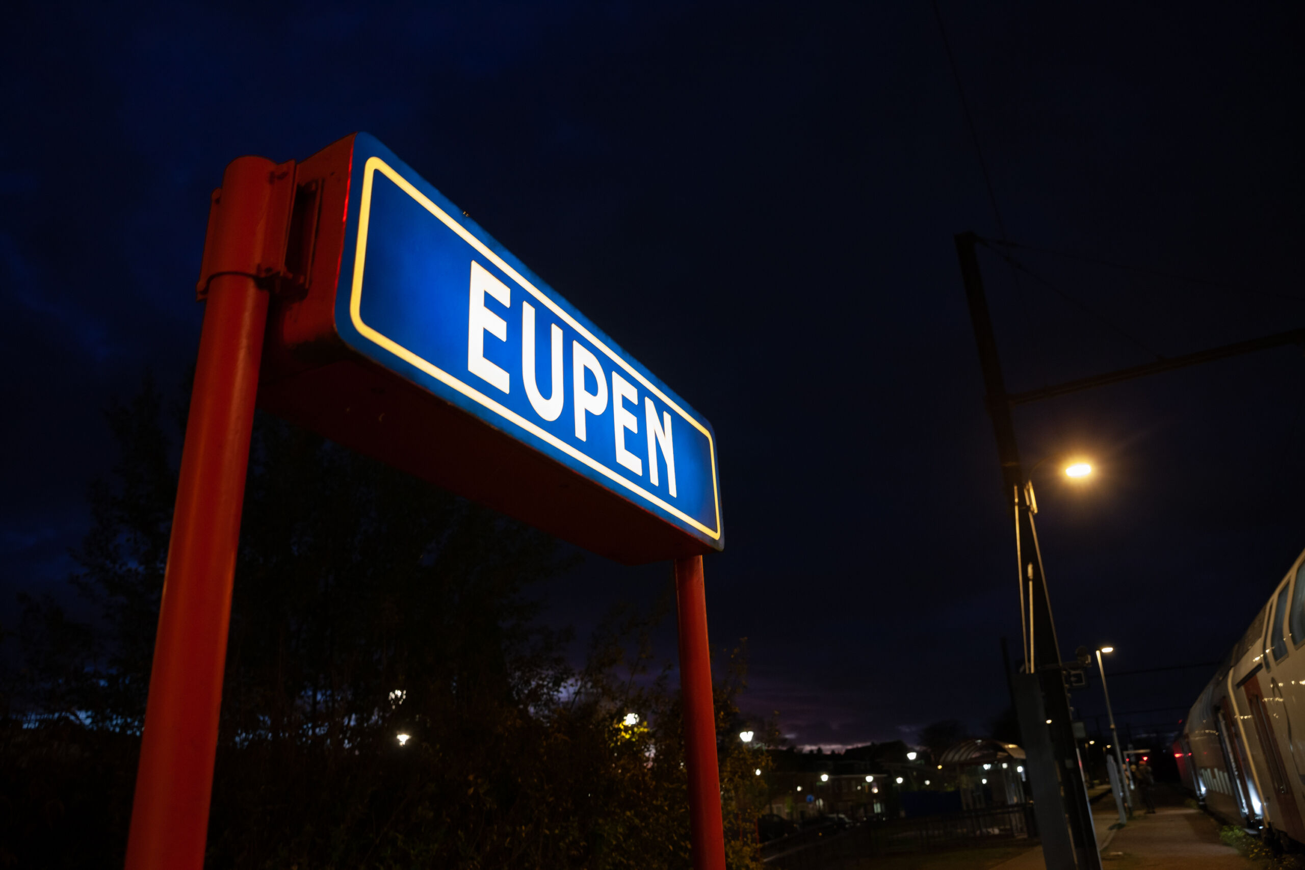 selective blur on a sign at the train station of eupen, lit at night, indicating the name of the city. eupen is a belgian city, capital of the german community of belgium.