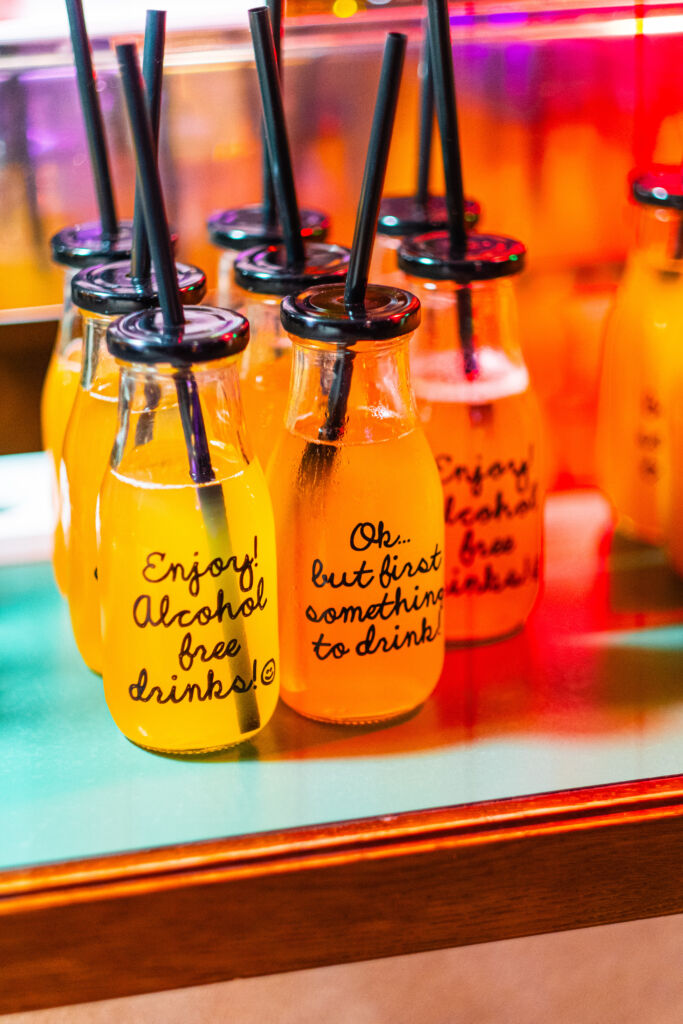 brightly colored bottles of alcohol free drinks on display with black straws and humorous labels for a refreshing party atmosphere