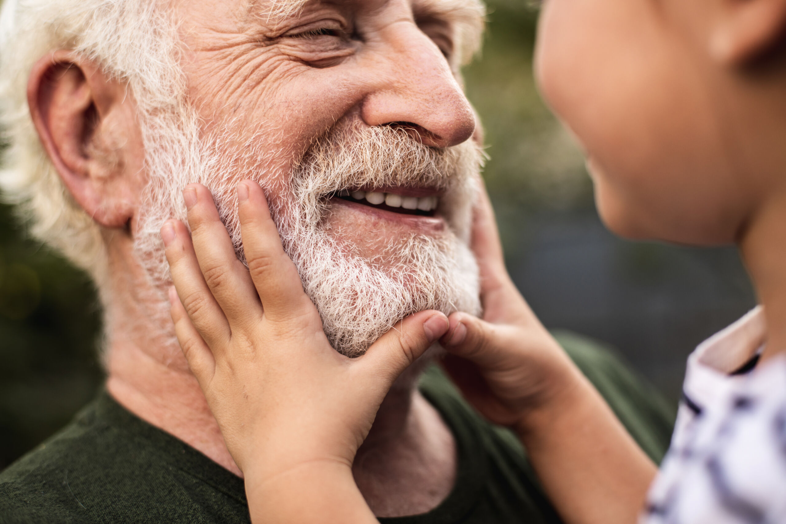 old smiling man and his granddaughter looking each other