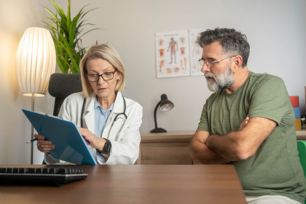 smiling female doctor meeting mature male patient in the clinic, providing professional care and consultation, creating a positive and supportive healthcare environment.