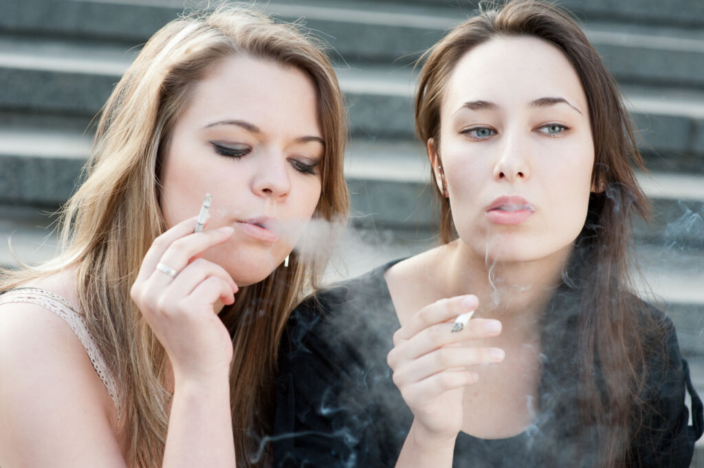 two sad young girls smoke