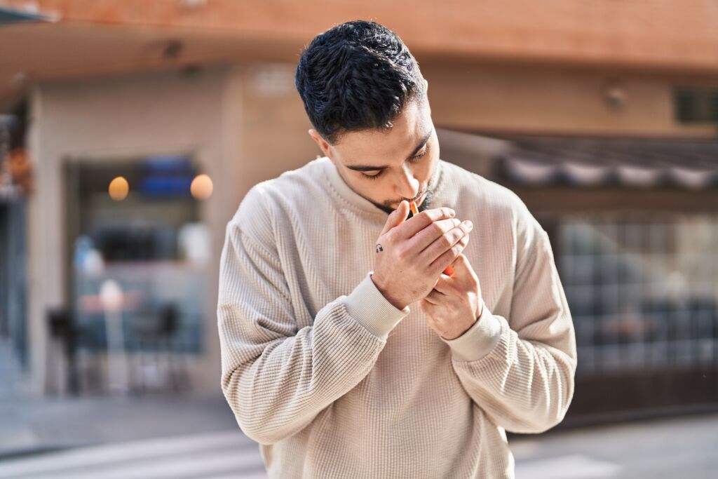 young arab man smoking with relaxed expression at street