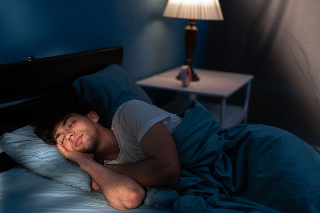 peaceful young man sleeping in a comfortable bed alone at home, enjoying his orthopedic mattress and cozy pillow. good sleep concept.