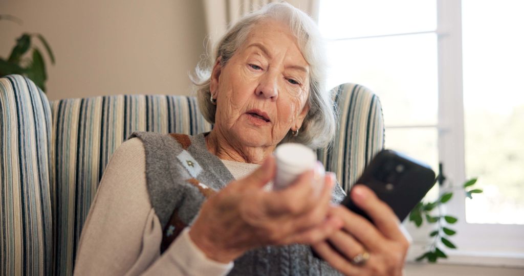 retirement, pills or old woman in home with phone, care research or medication in health treatment. medical, tech or senior person with bottle, dosage instruction or prescription guidance in recovery