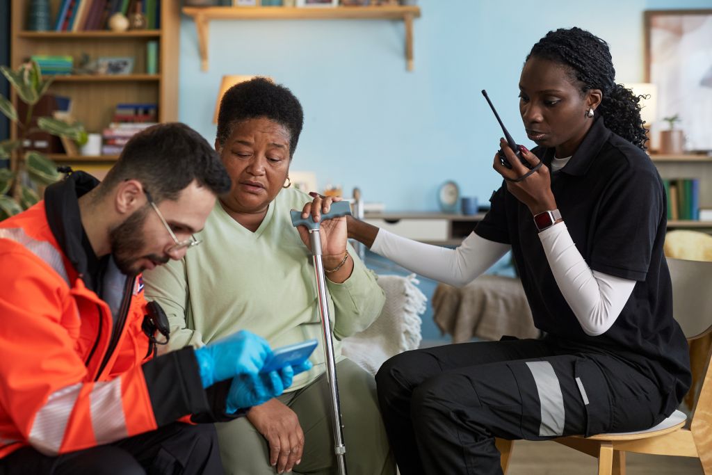 middle aged black woman receiving assistance from paramedics indoors